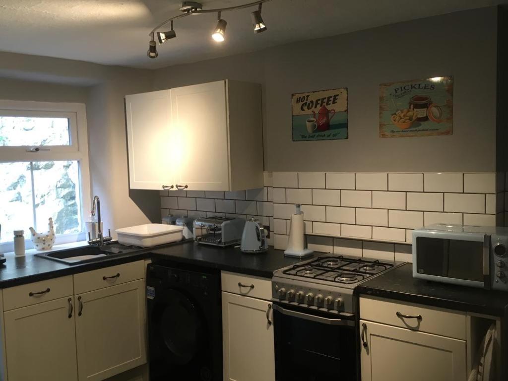 a kitchen with a stove and a microwave at Blue Sky Cottage in Matlock