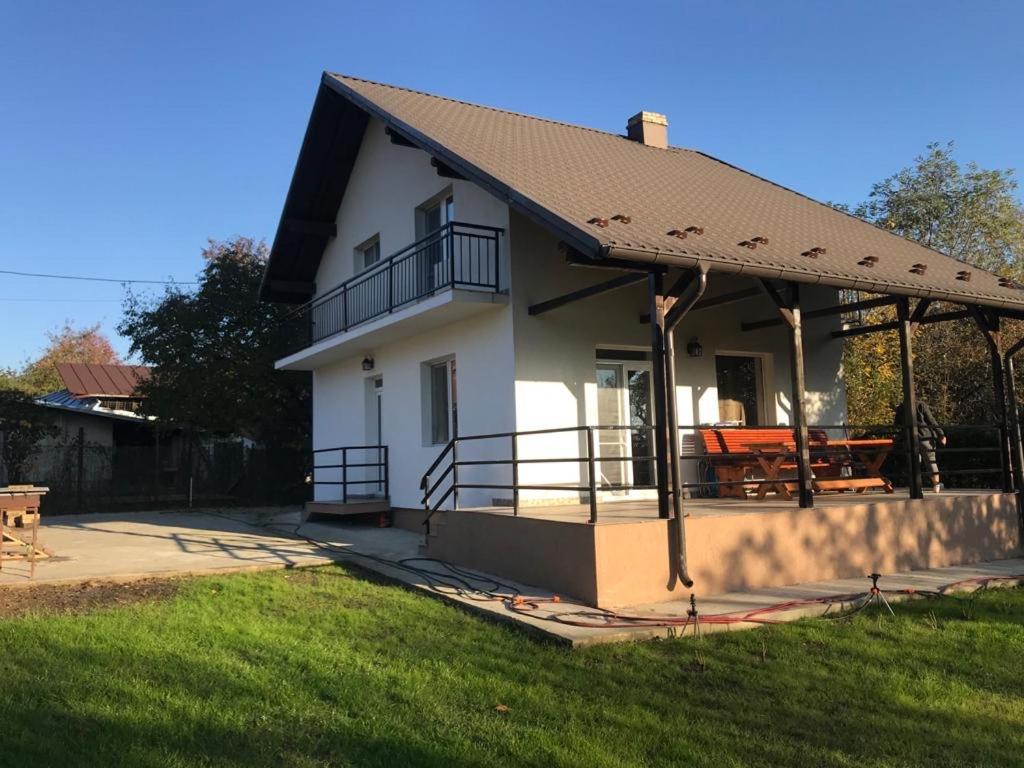 ein weißes Haus mit einem Dach und einem Grasfeld in der Unterkunft Green Nest in Băneşti