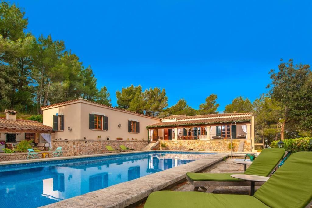 a house with a swimming pool with green lounge chairs at Finca Es Collet in Felanitx
