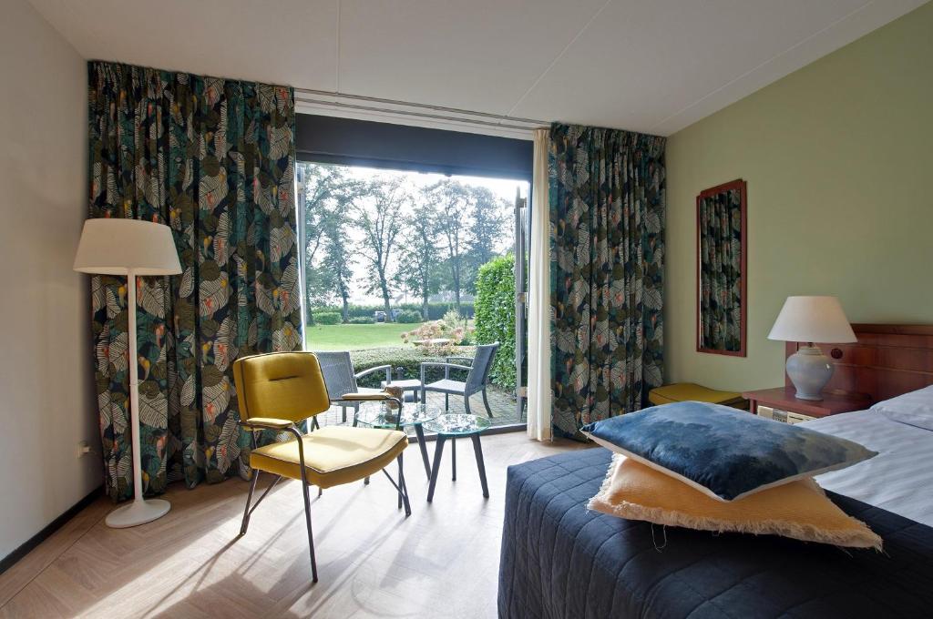 een slaapkamer met een bed en een tafel en stoelen bij Boetiek Hotel BonAparte Lochem in Barchem