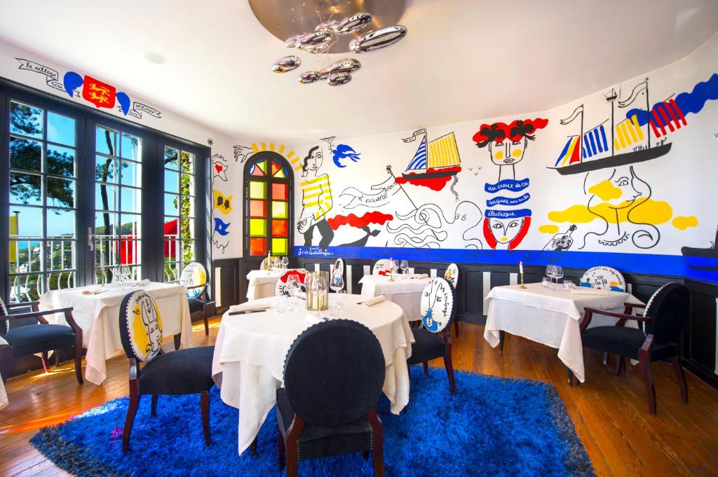a restaurant with tables and chairs and a mural at Domaine Saint Clair - Le Donjon in Étretat