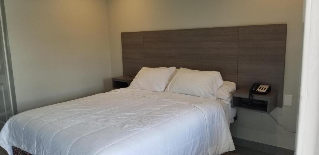 1 dormitorio con cama blanca y cabecero de madera en Maxim III Motel en Houston