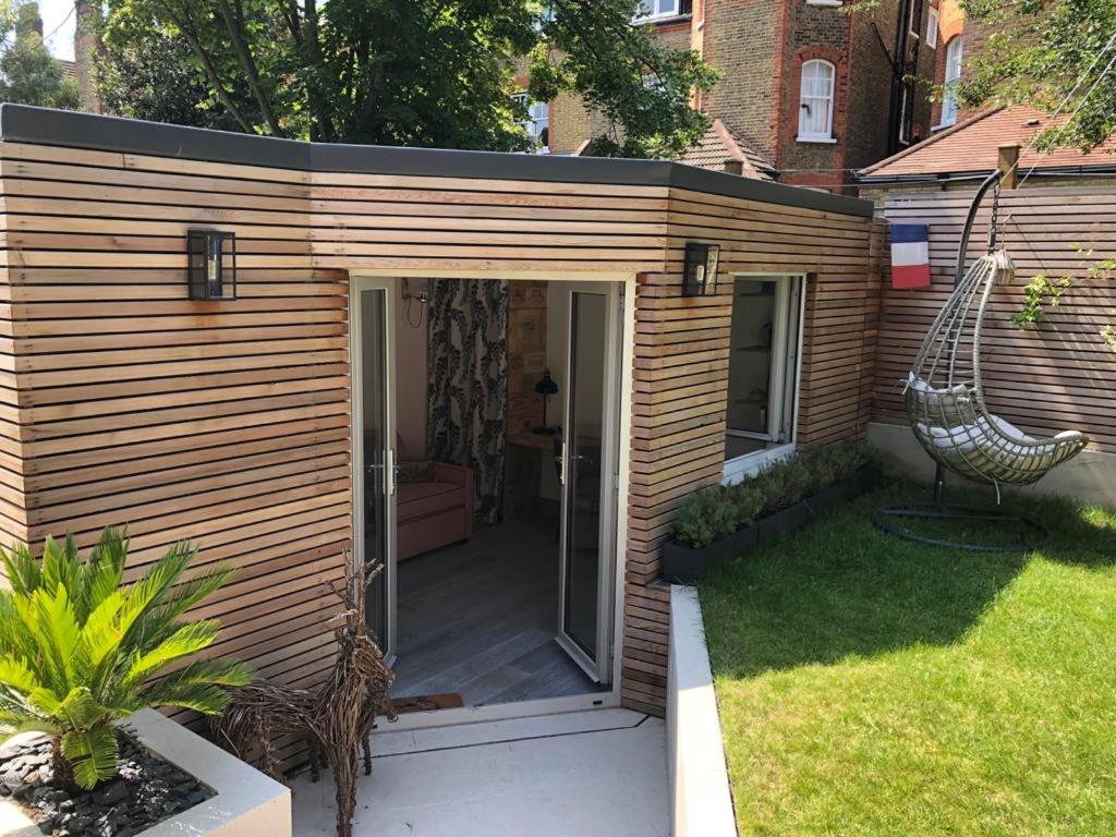 un pequeño cobertizo de madera con un columpio en un patio en Independent garden study, en Londres