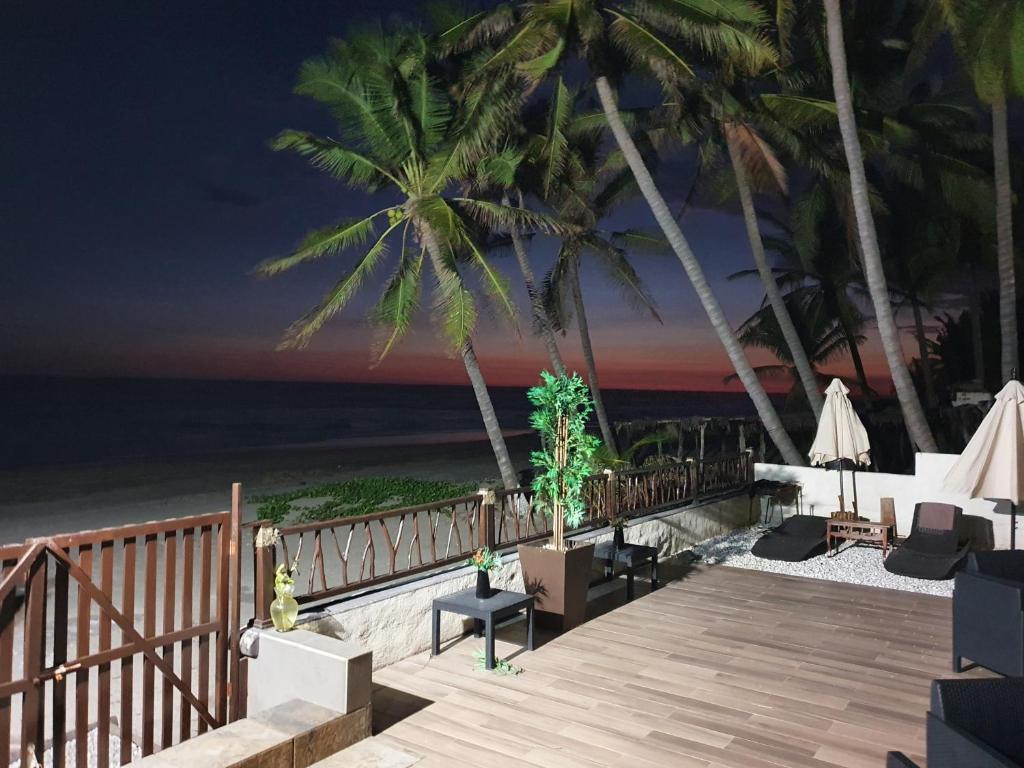 una terrazza in legno con sedie e palme sulla spiaggia di Bungalows La Perla Playa Azul a Playa Azul