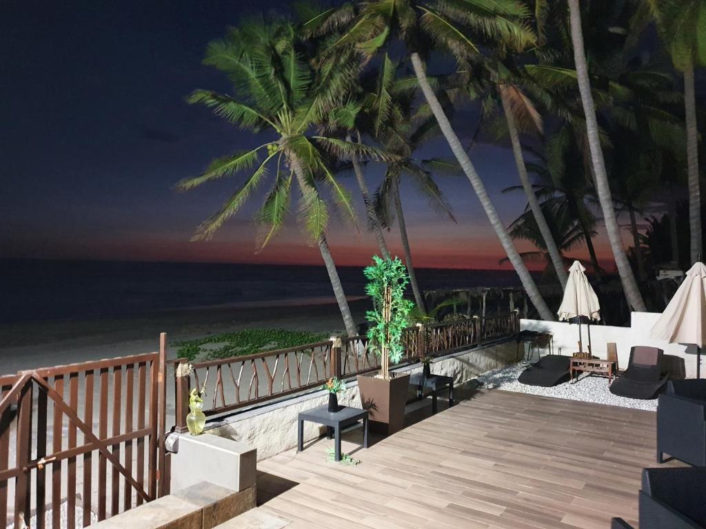 una terraza de madera con sillas y palmeras en la playa en Bungalows La Perla Playa Azul, en Playa Azul