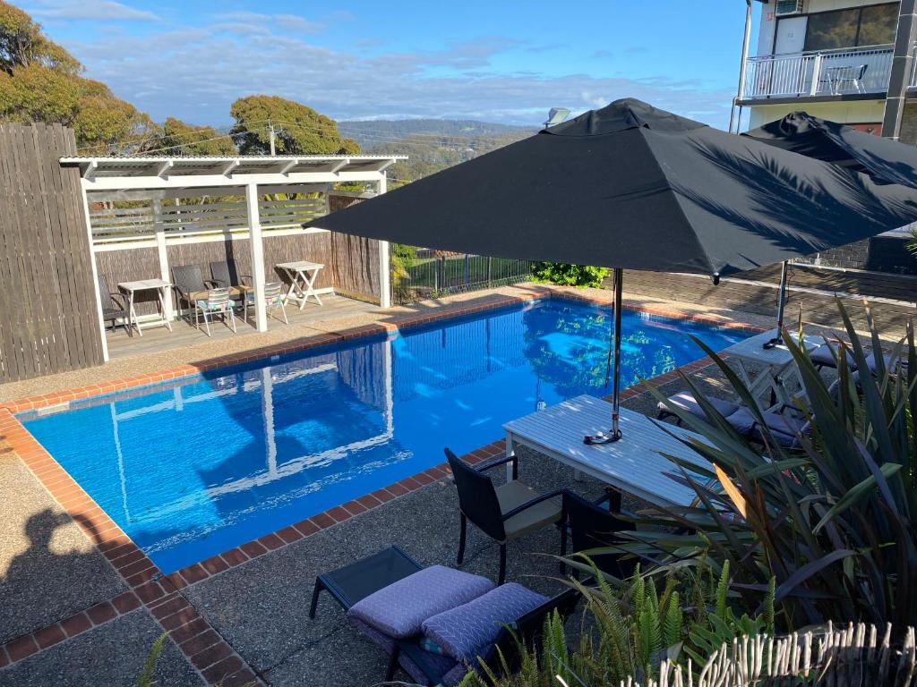 a pool with an umbrella and a table and chairs at Top of the Town Motor Inn in Narooma