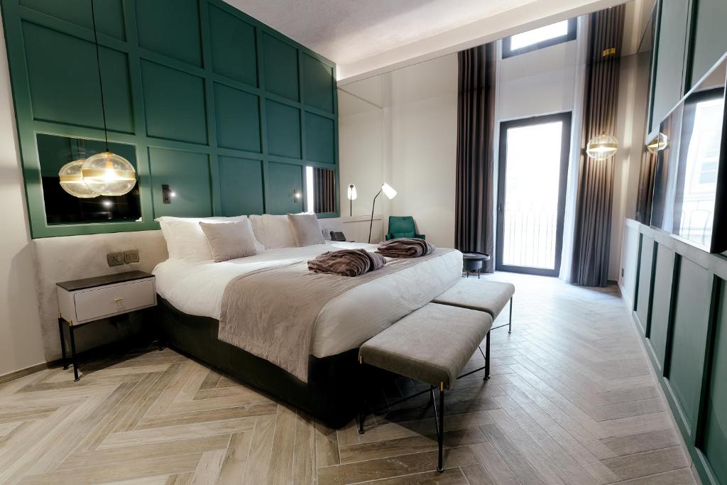a bedroom with a large bed with a green wall at The Embassy Valletta Hotel in Valletta