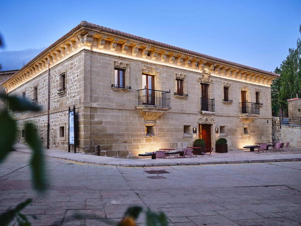 - un grand bâtiment en pierre avec des tables et des chaises devant dans l'établissement Palacio de Samaniego, à Samaniego