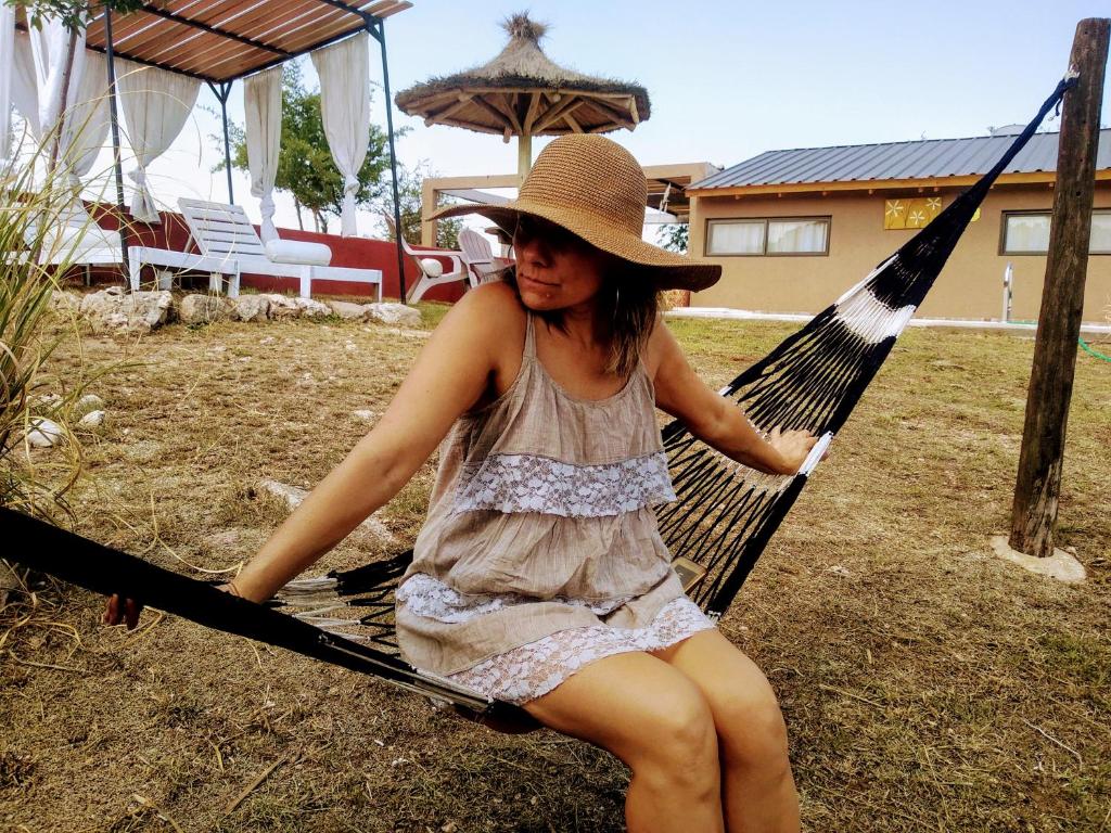 Una chica con sombrero sentada en una hamaca en Los Frutales en Villa Carlos Paz