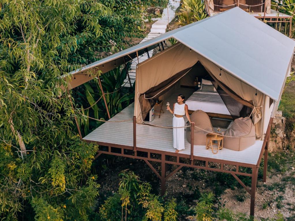 a woman standing in a tent in a forest at Autentik Penida "Glamping" - Adults only in Nusa Penida
