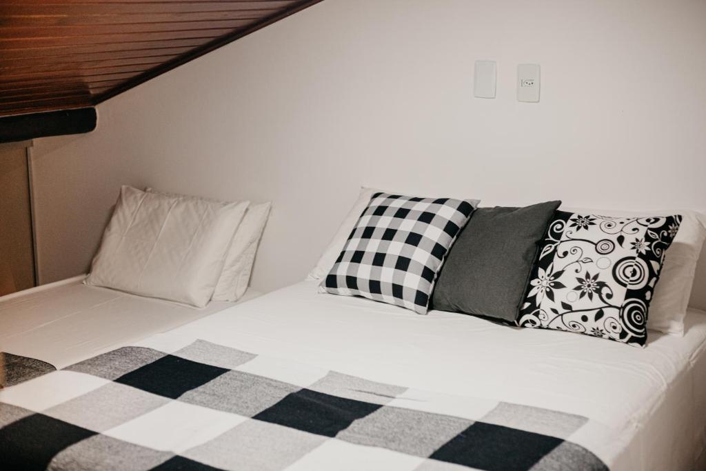 a bed with black and white pillows on it at FLAT MODERNO E ACONCHEGANTE in Gravatá