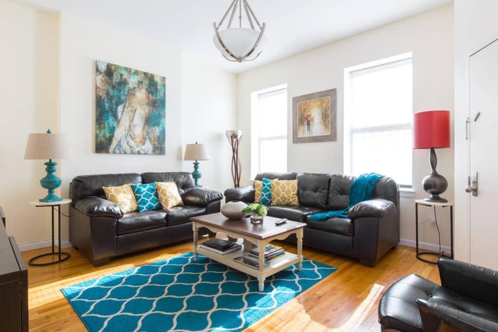 Elegant and Comfortable Stay في بروكلين: غرفة معيشة مع أريكة جلدية وسجادة زرقاء