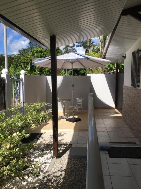 a patio with an umbrella and a table and chairs at Les gardénias in Matoury