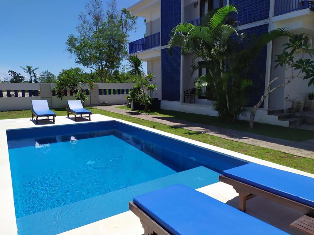 a swimming pool with two chairs and a house at Sea Star Bali in Uluwatu