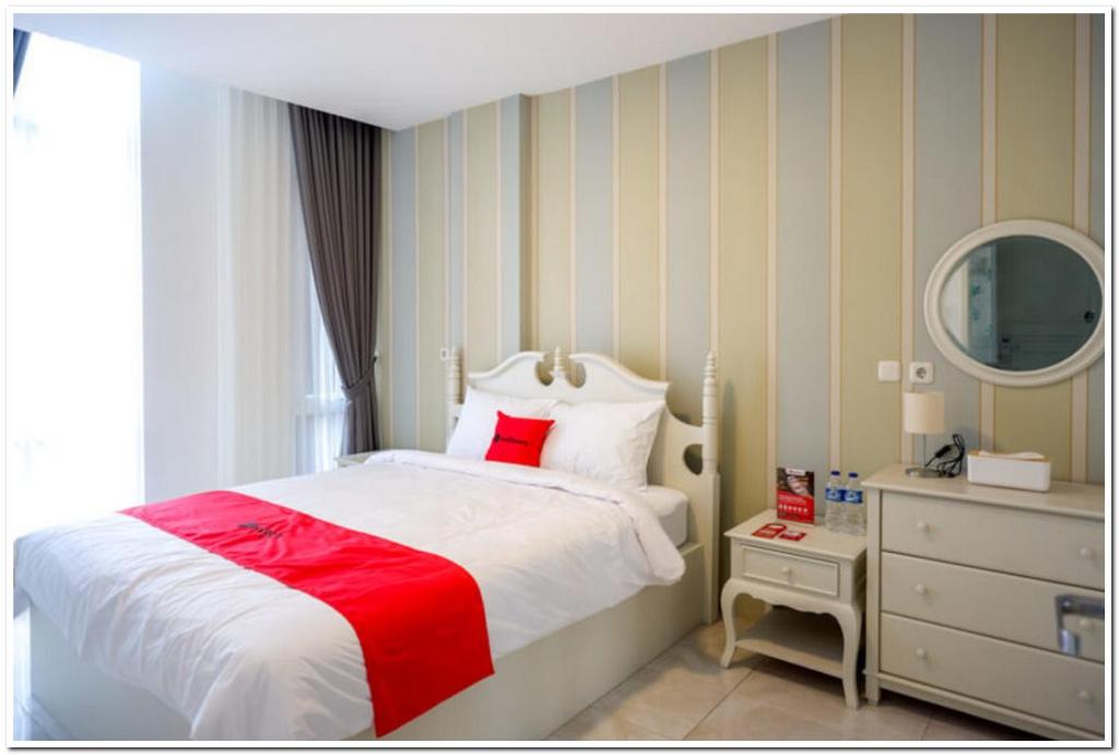 Un dormitorio con una cama roja y blanca y un espejo en RedDoorz Plus @ Madukoro Raya Semarang en Kalibanteng-lor