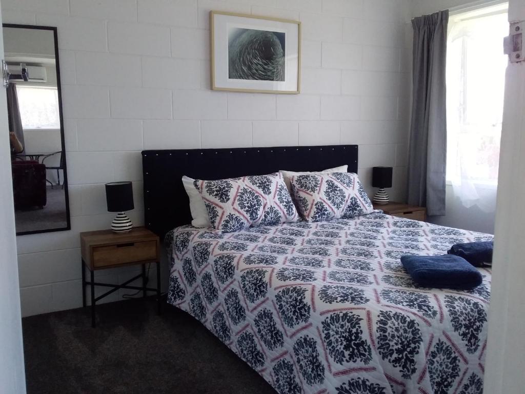 Schlafzimmer mit einem Bett mit einer blauen und weißen Bettdecke in der Unterkunft Fantastic Two Bedroom Unit in Whakatane