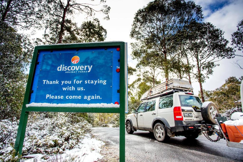 a truck parked on the side of a road near a sign at Discovery Parks - Cradle Mountain in Cradle Mountain