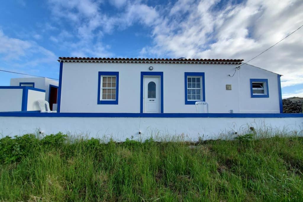 una casa blu e bianca in cima a un campo di casa Eira Alta a Santa Bárbara