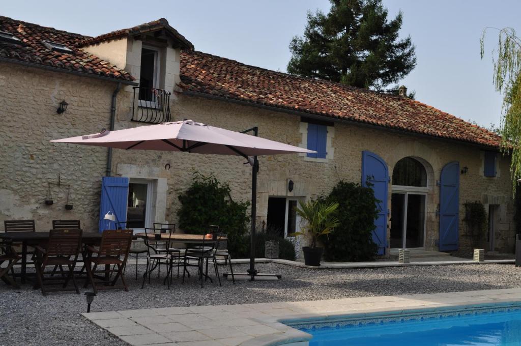 eine Terrasse mit einem Tisch und einem Sonnenschirm neben einem Haus in der Unterkunft Chambres d'Hôtes La Grange Au Bois in Champagne-et-Fontaine