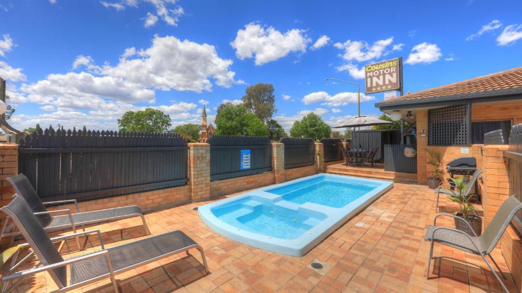a swimming pool on a patio with chairs and a building at Cousins Motor Inn in Inverell