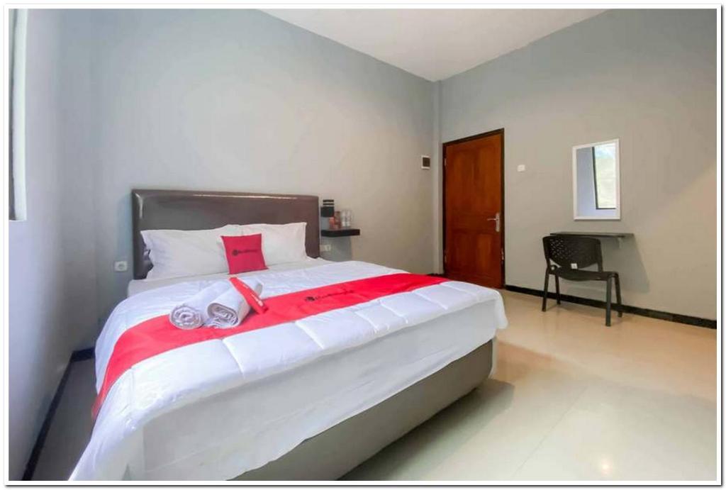 a bedroom with a large bed with towels on it at RedDoorz Syariah near T2 Juanda Airport 2 in Dares