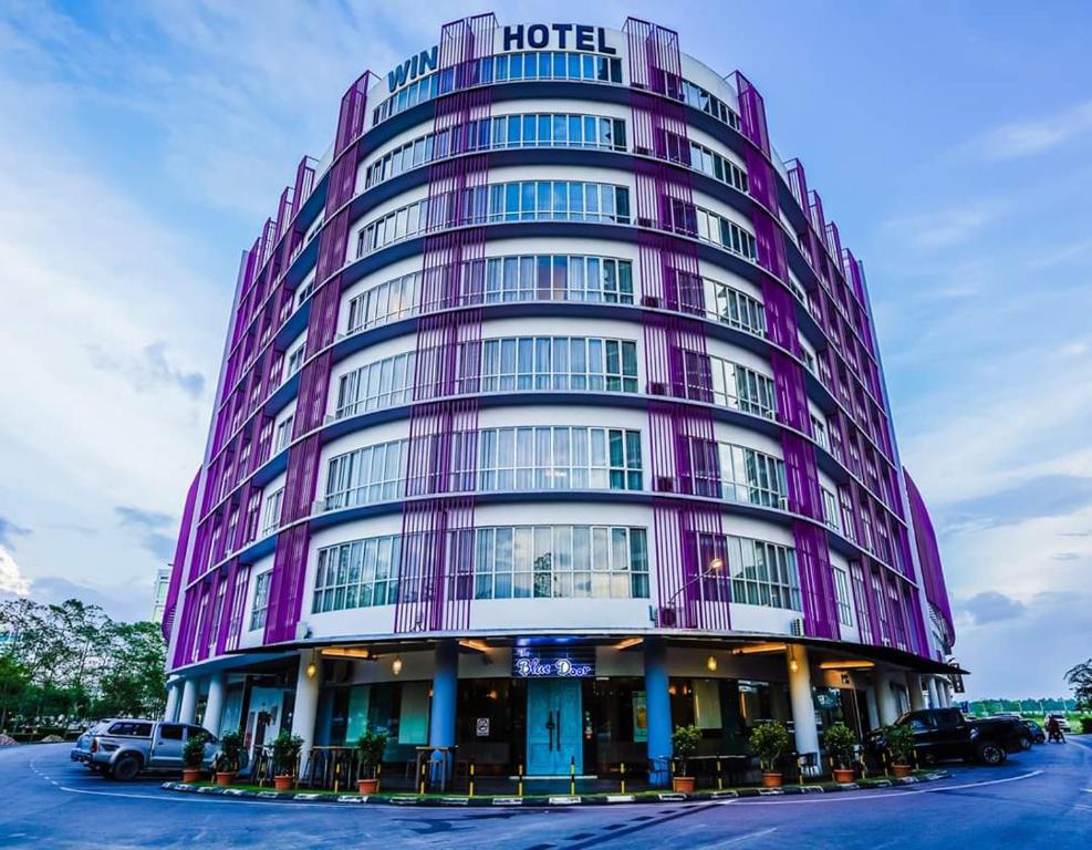 a purple hotel building with cars parked in a parking lot at Win Hotel in Sibu