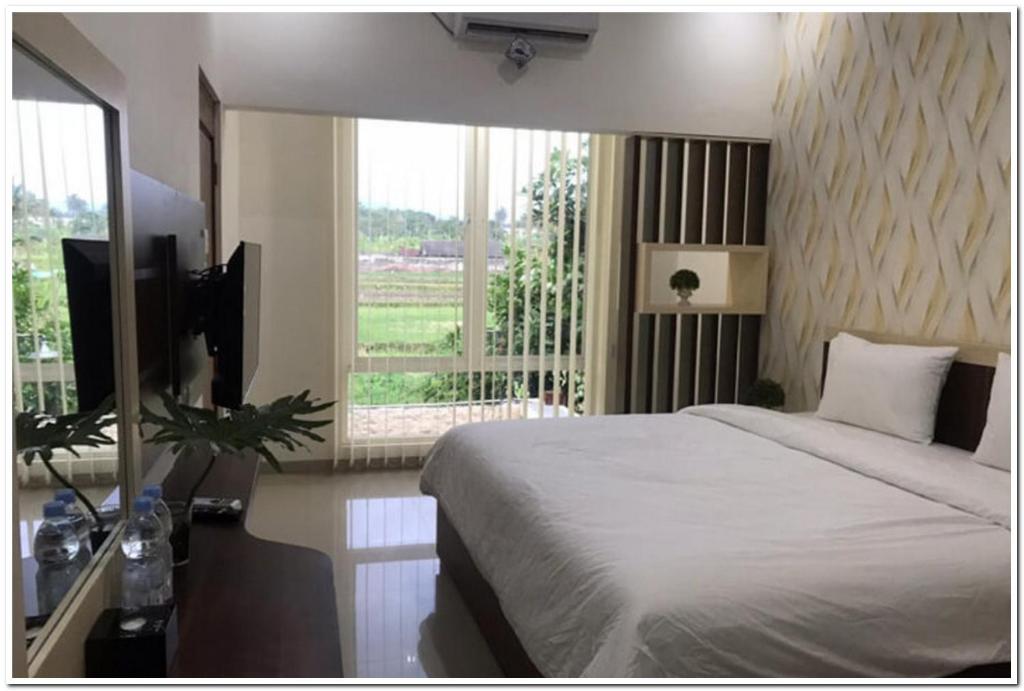 a bedroom with a bed and a television and a window at RedDoorz Syariah at Omah Sawah in Balong