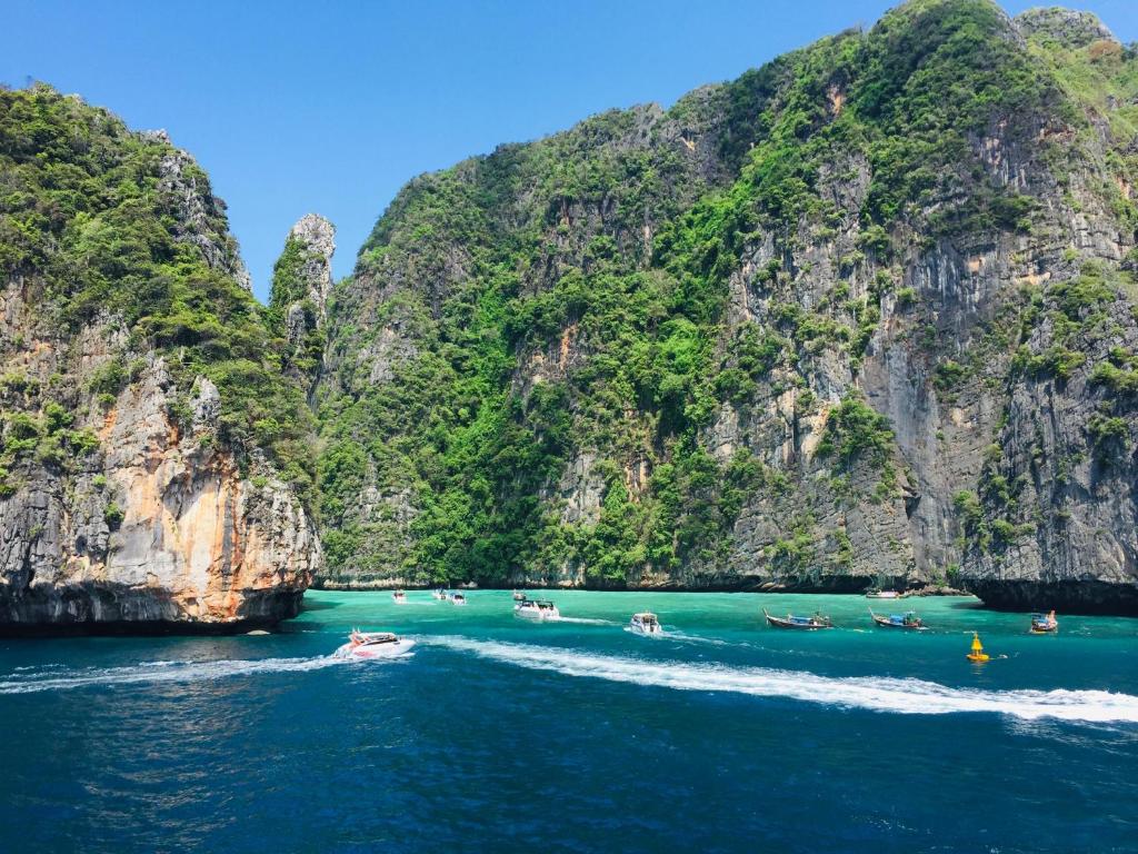 a group of people in boats in the water near cliffs at The Mantra Hotel Kata Noi in Kata Beach