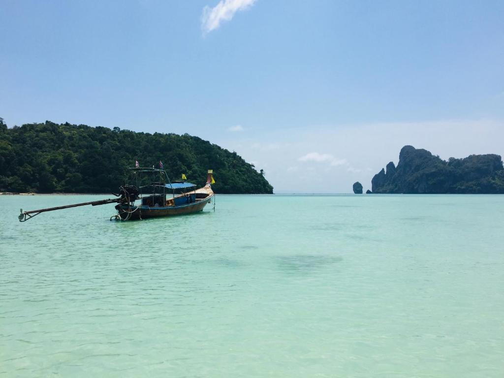 a boat sitting in the water near a island at The Mantra Hotel Kata Noi in Kata Beach