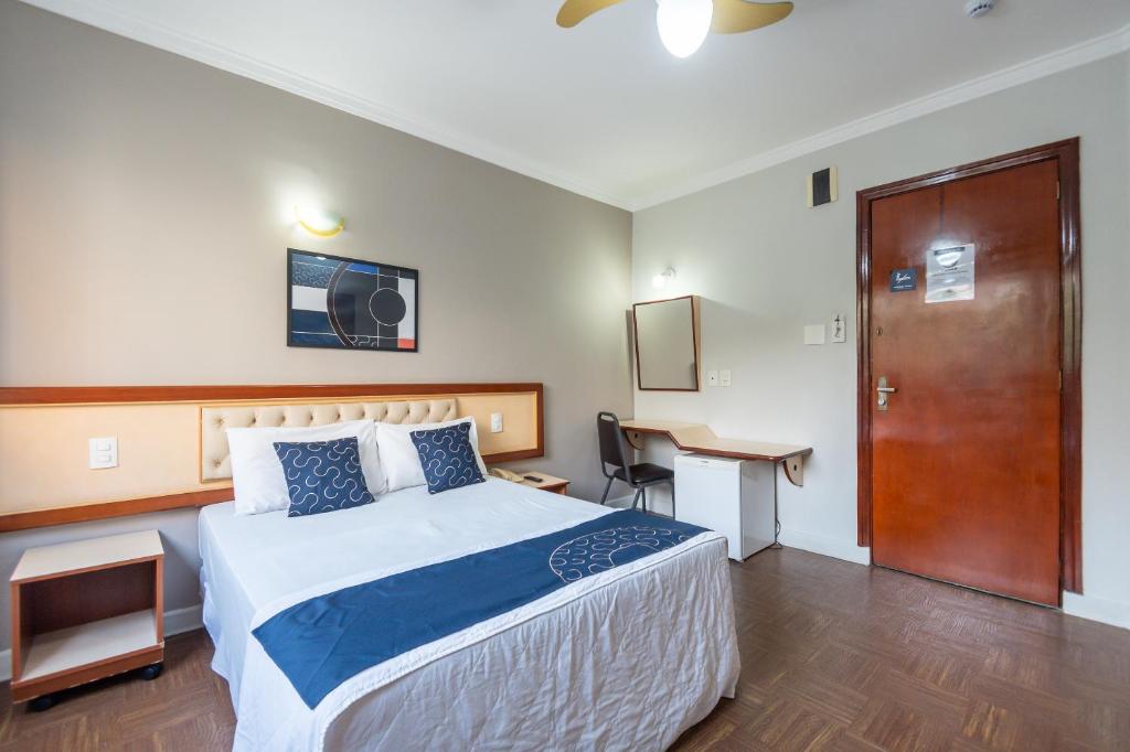 una camera d'albergo con letto, scrivania e porta di Hotel Piratininga, Sao Paulo a San Paolo