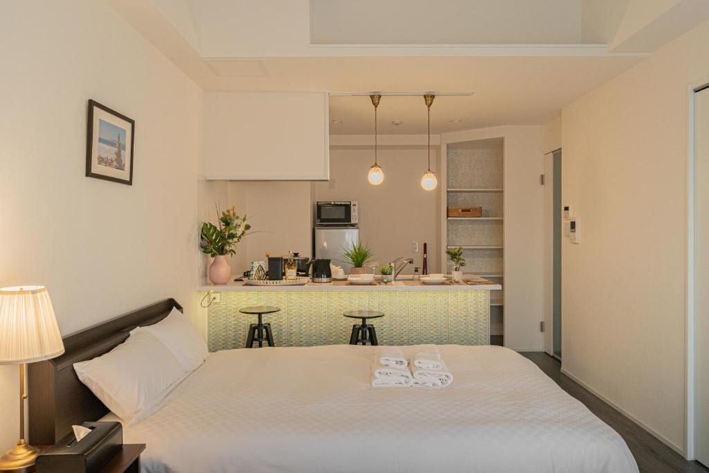 a bedroom with a large white bed and a kitchen at 谷町君ホテル WE 難波28 in Osaka