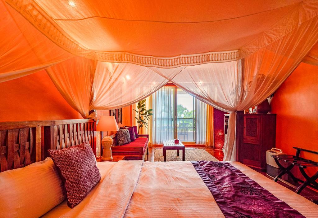 a bedroom with a large bed with an orange wall at Red Garden Resort in Eluan