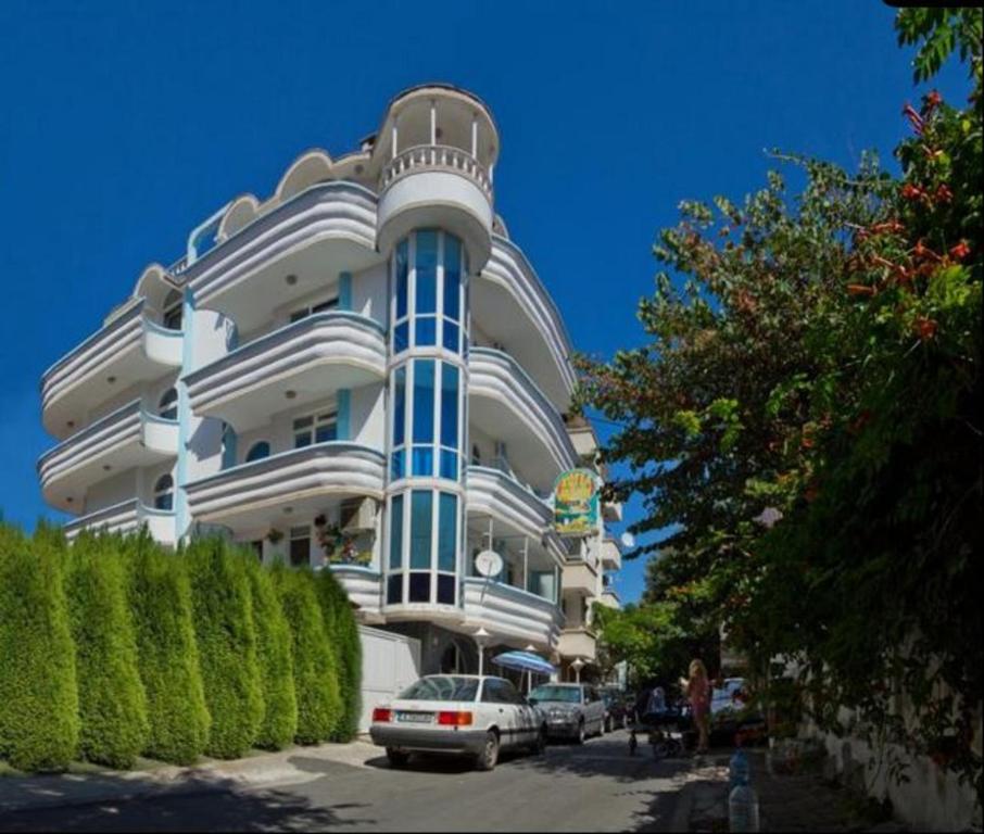 a large white building with cars parked in front of it at Family Hotel Paros 2 in Pomorie