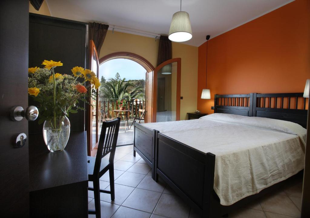 1 dormitorio con 1 cama y un jarrón de flores sobre una mesa en B&B Villa Rodriguez, en Milazzo