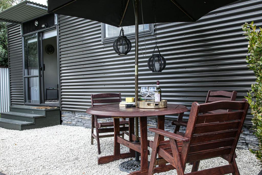 un tavolo in legno con sedie e un ombrellone su un patio di HOH - Chalet Frodo a Matamata