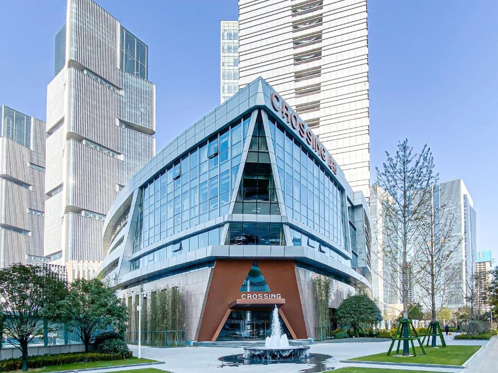 un grand bâtiment en verre dans une ville avec de grands bâtiments dans l'établissement Zhengzhou Crossing Hotel, à zhengzhou