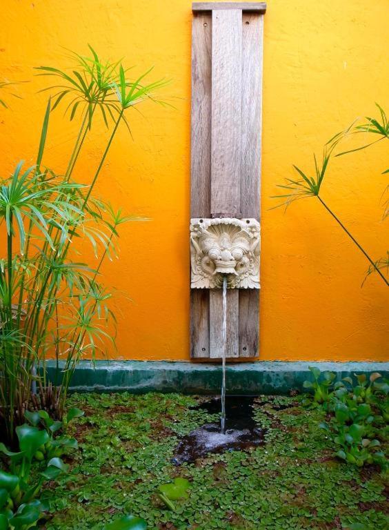 a yellow wall with a fountain in a garden at Red Garden Resort in Eluan