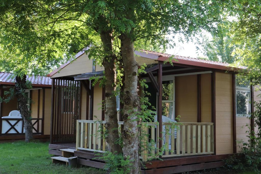 Avrillé的住宿－Camping les Mancellieres，前面有一棵树的小房子