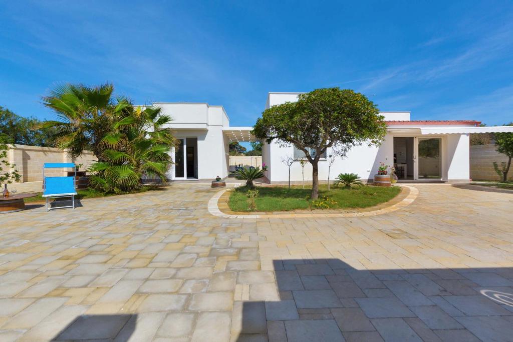 una casa blanca con una silla azul delante en Villa Il Fenicottero Salentino by BarbarHouse, en San Pietro in Bevagna