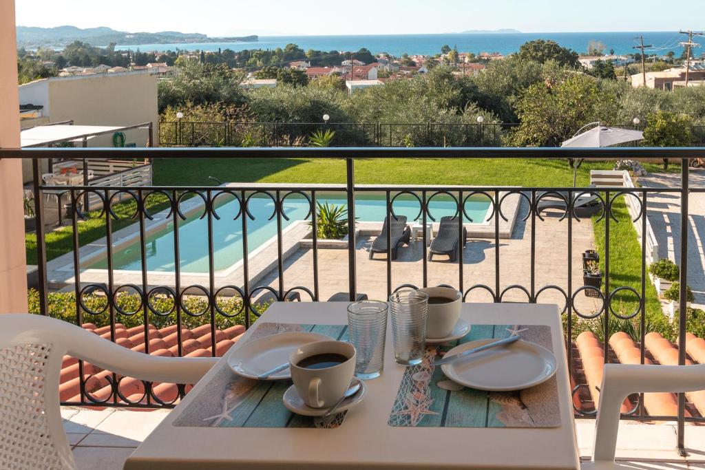 a table with two cups of coffee on a balcony at Catamaran Corfu Aparthotel in Acharavi