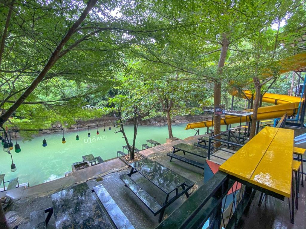 Blick auf einen Fluss mit Bänken und Bäumen in der Unterkunft Natthapon Resort Kaeng Kachan in Kaeng Kachan