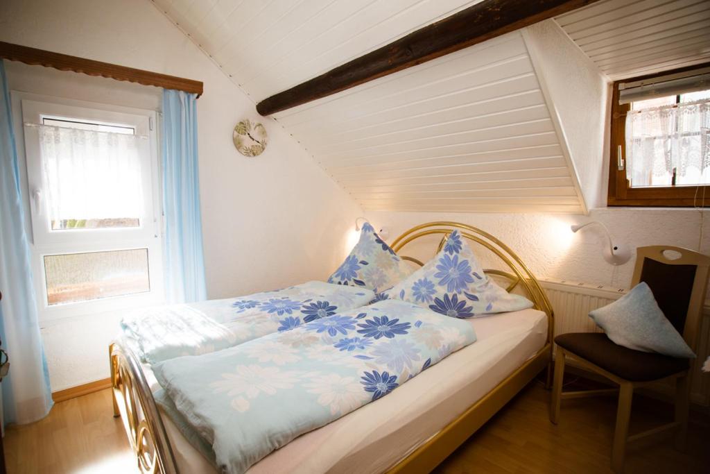 ein Bett mit blauer und weißer Bettwäsche und einem Fenster in der Unterkunft Pension Haus Andreas in Cochem
