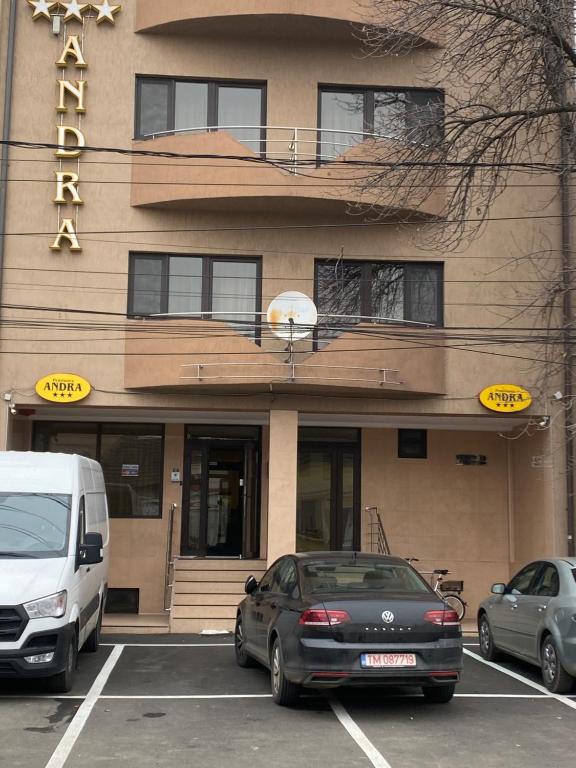 dos coches estacionados en un estacionamiento frente a un hotel en Pensiunea Andra en Timisoara