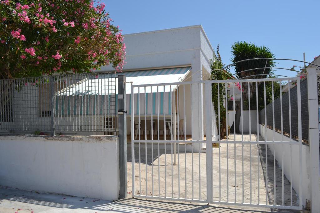 um portão em frente a uma cerca branca em Cala Rosa em Torre Lapillo