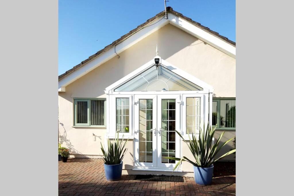 a house with a conservatory with two potted plants at Cherry Cottage - Perfect base for two in beautiful Pembrokeshire in Begelly