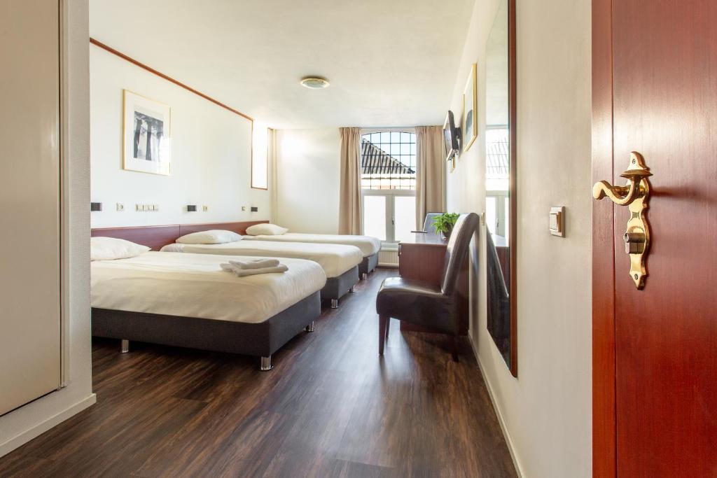 una habitación de hotel con 3 camas y una puerta en Het Wapen van Leiden, en Appingedam