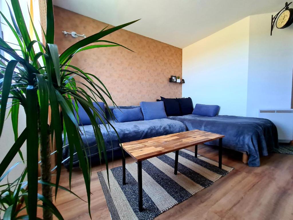 uma sala de estar com um sofá azul e uma mesa em Logement entier 30m² - 800m du Futuroscope em Chasseneuil-du-Poitou