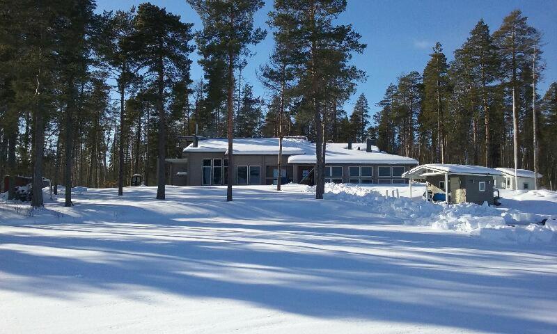 a house in the snow in front of trees at Chalet Norva in Rovaniemi