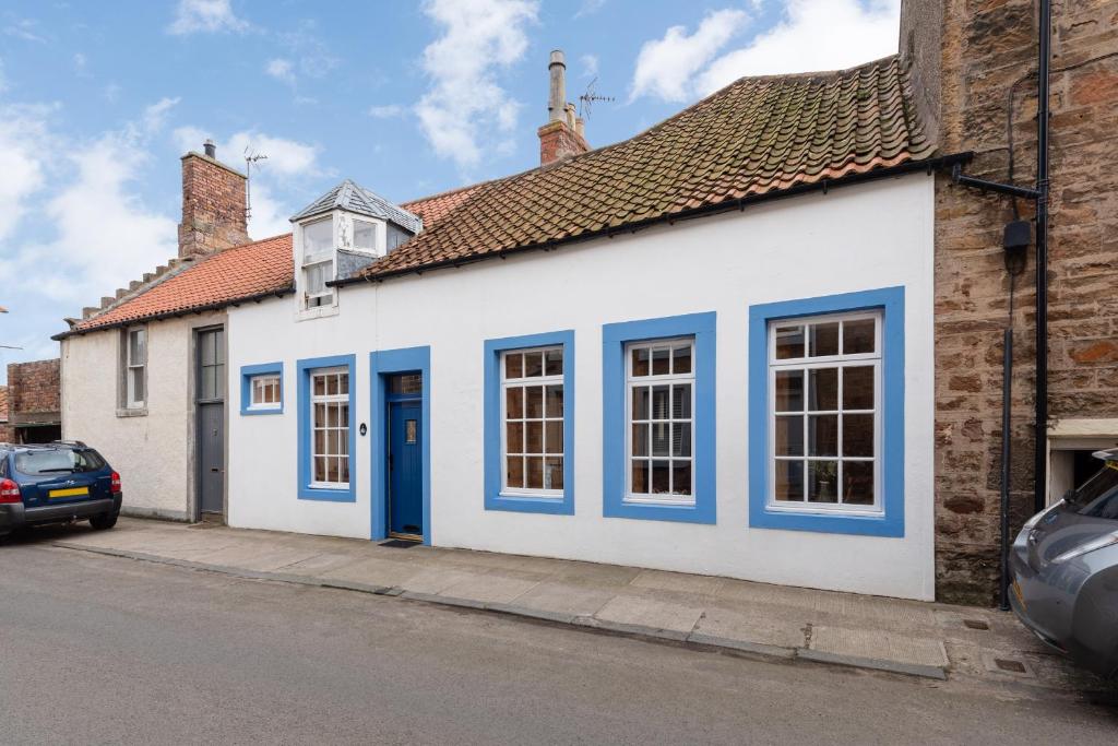 un edificio blanco con puertas azules en una calle en Coastal Cottage - Cellardyke Anstruther, en Anstruther