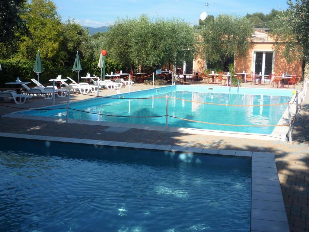 a large swimming pool with tables and chairs in front of a building at Apartment Borgoverde-1 by Interhome in Imperia